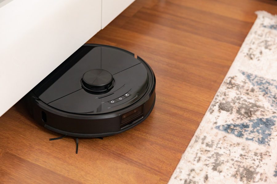 Robot vacuum cleaner cleaning a wooden parquet in living room.